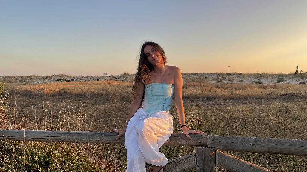 Lia Coll, creativa publicitaria junior, sentada en una valla al atardecer